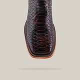 A close-up of the Exotic Python - Black Cherry - Square Toe boot showcases its dark, textured python leather against a light gray background, emphasizing its intricate detail reminiscent of exotic elegance.