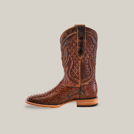 The Exotic Python - Brown - Square Toe cowboy boot is crafted from rich brown leather, with intricate stitching and textured patterns. The design features a square toe and low heel on a plain beige background, highlighting the elegance of classic cowboy boots.