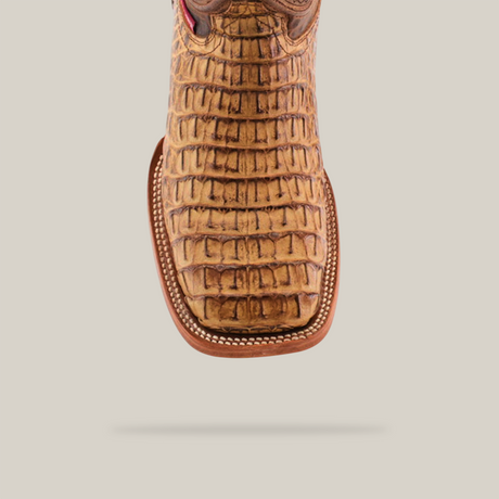 The Exotic Caiman Horn Back - Biza Camel exhibits a crocodile texture and square toe with intricate stitching, standing out against a plain light backdrop.