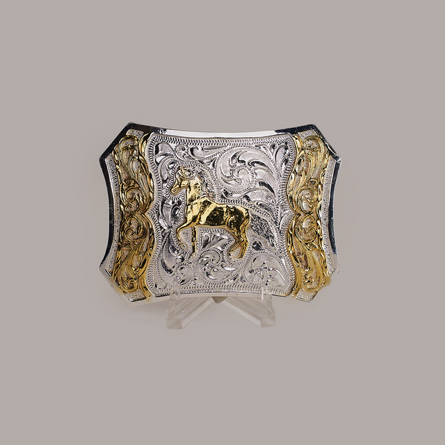 The Spade Horse Buckle is a rectangular Texas-style buckle made from alpaca silver, featuring ornate engravings with a central gold horse motif. Intricate swirling patterns and gold accents on each side finish this classic western design.