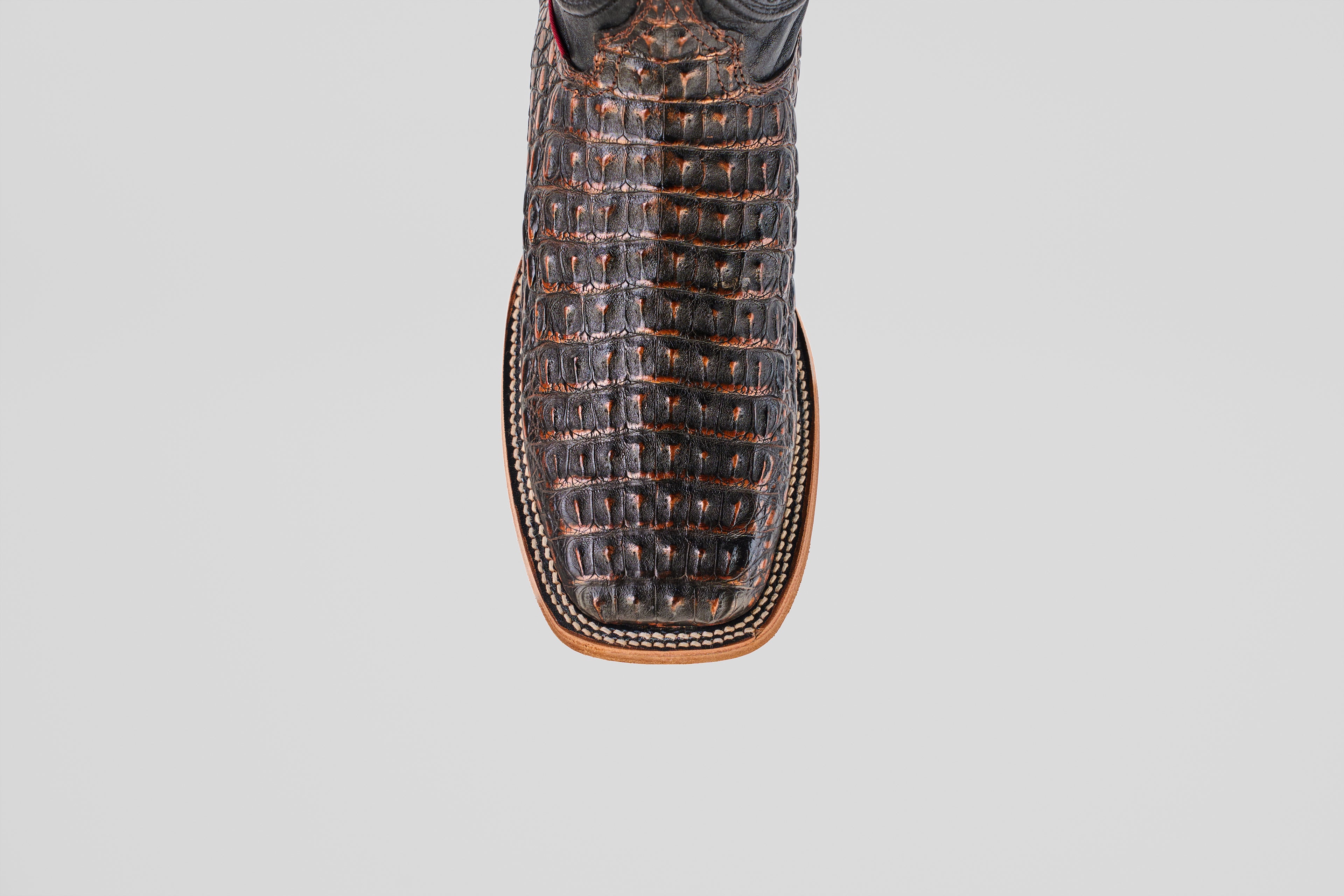 Close-up top view of the Exotic Caiman Horn Back - Roma boot, featuring brown textured caiman leather, a square toe, and detailed edge stitching, set against a plain white background.