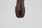 A close-up, top-down view showcases the unique texture of the Exotic Caiman Hornback - Brown - Rodeo Toe boots square toe in genuine caiman leather against a plain light gray background.