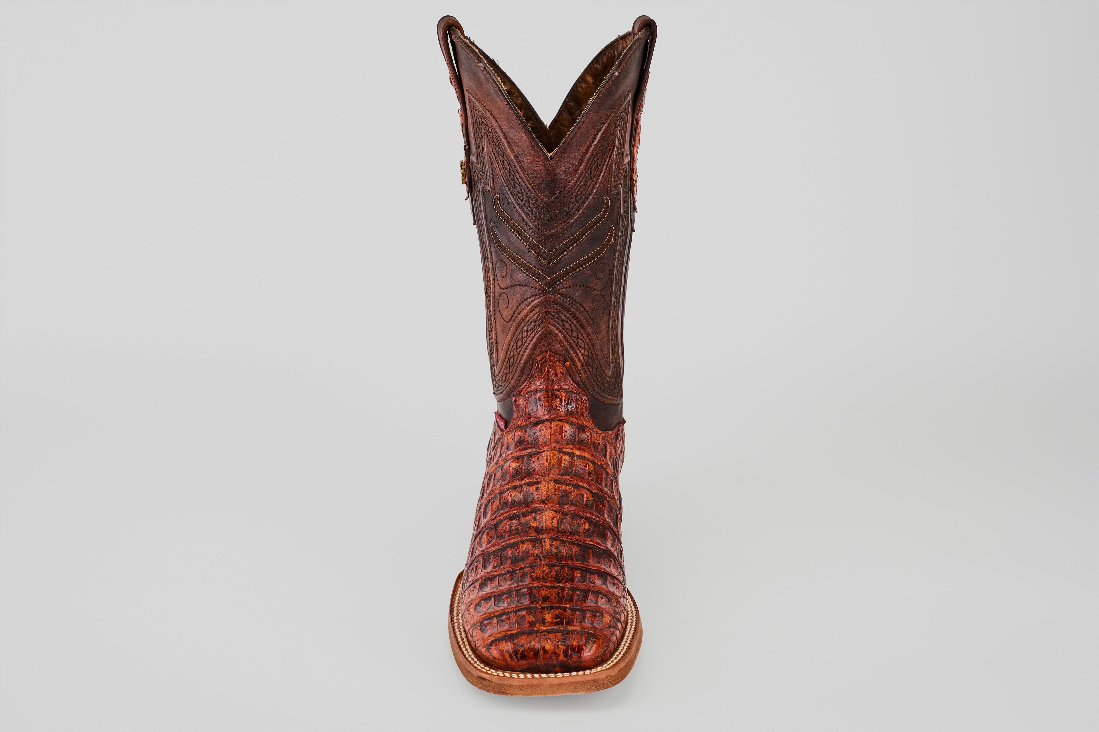 The Exotic Caiman Horn Back - Smoke Cogñac- Square Toe boot features textured caiman leather with decorative stitching, shown from the front against a plain light gray background.