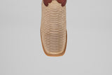 A close-up, top-down view of the Braxton - Cappucino boot features beige python leather, a dark brown accent at the top, and a textured square toe design.