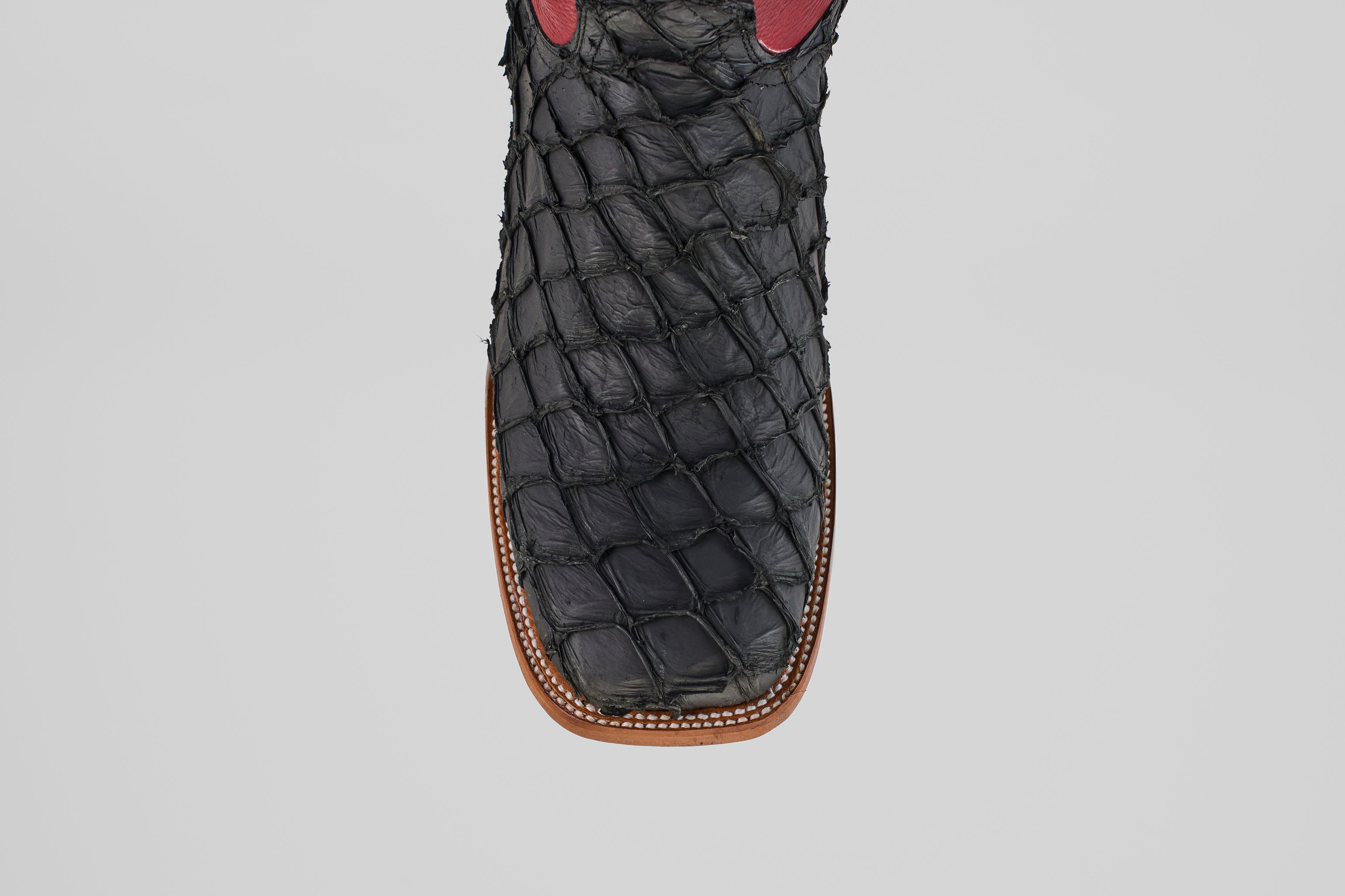 A top view close-up of the Dodge - Matte Black - Square Toe boot showcases its textured Pirarucu leather, square toe design, and brown stitching along the sole—an exemplar of mens luxury boots.