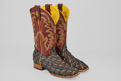 A pair of Butch - Caramel - Square Toe cowboy boots featuring textured, dark brown Pirarucu leather on the foot and maroon shafts with yellow stitching, set against a light gray background.