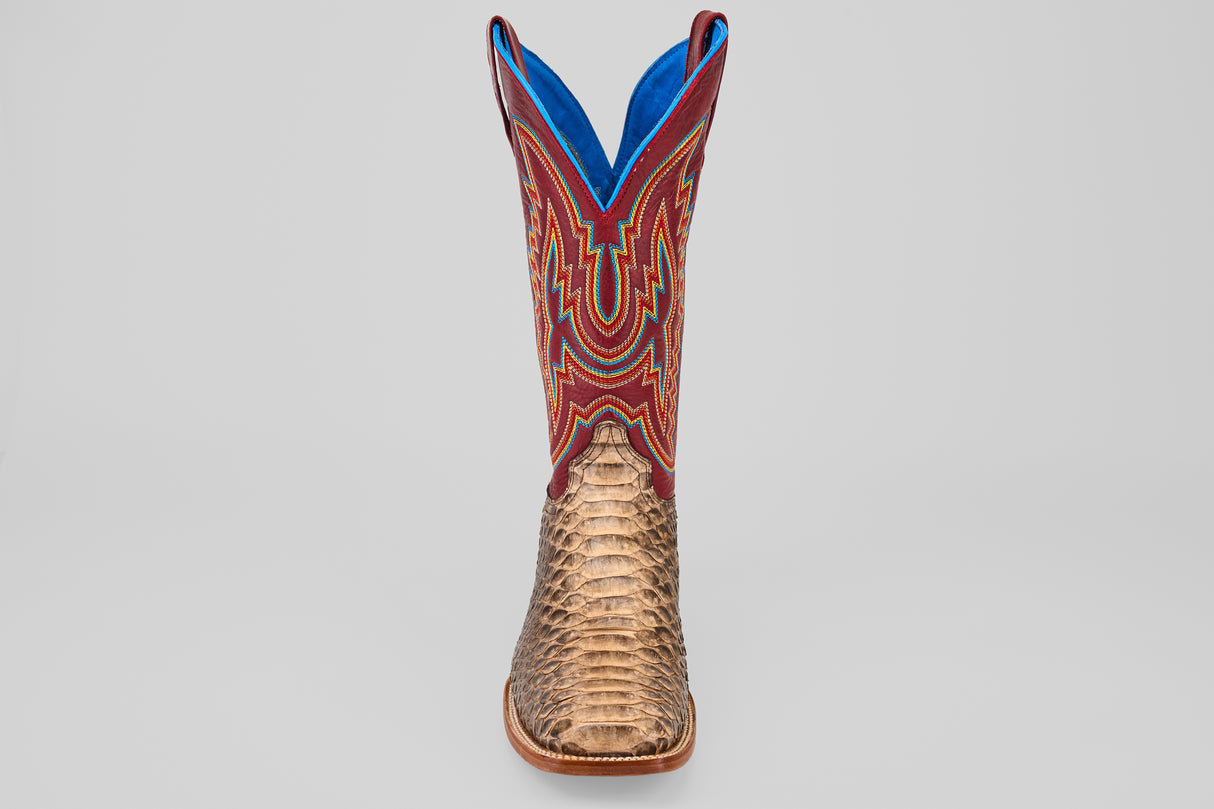 The Barlow - Taupe - Square Toe men’s statement boot features a textured taupe python leather lower, a vibrant red upper with blue and yellow stitching, and is displayed front-facing against a plain gray background.