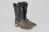 A pair of Exotic Pirarucu Fish - Newspaper - Square Toe boots, featuring black uppers, scale-patterned gray and black lowers, and light brown wooden heels and soles, displayed on a plain gray background.
