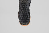 A close-up of the Exotic Pirarucu Fish boot in matte black, featuring a textured finish, square toe, and light brown sole, set against a plain light gray background.