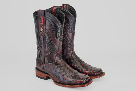 A pair of Exotic Ostrich - Black Cherry boots featuring rodeo toes, detailed shaft stitching, and a textured ostrich leather pattern. These boots combine striking black cherry color with sturdy construction.