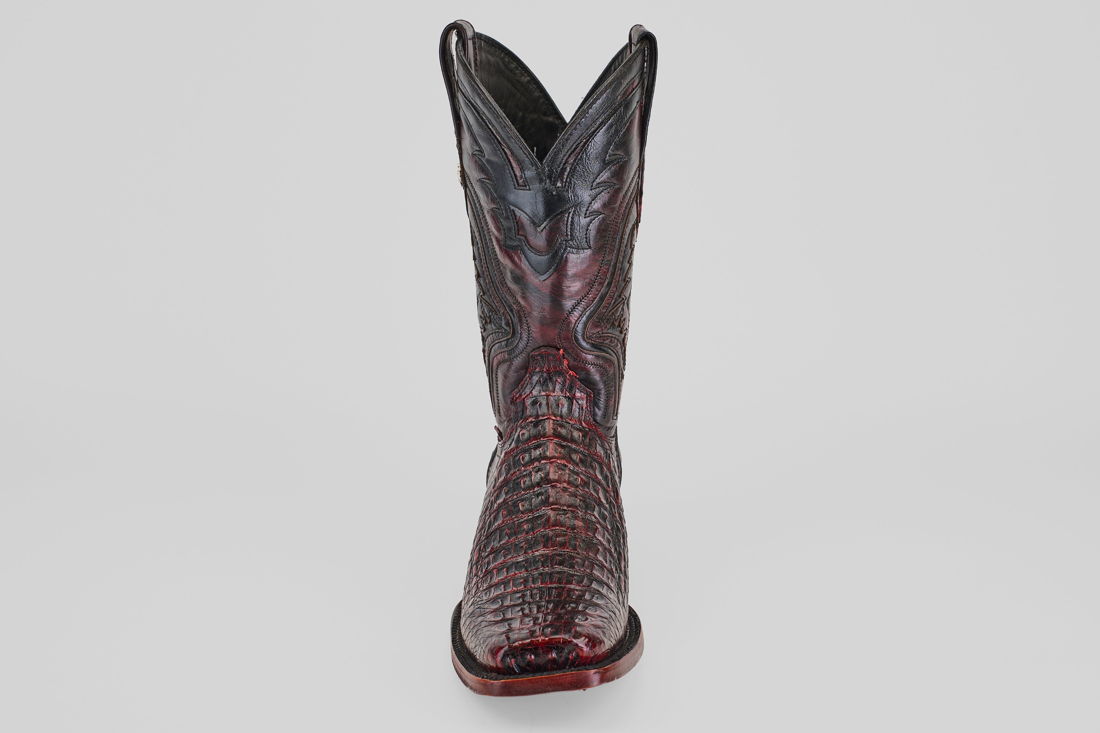 The Exotic Caiman Hornback - Blackcherry - Rodeo Toe boot, featuring a pointed toe, crocodile texture, and decorative stitching, stands upright against a plain light background.