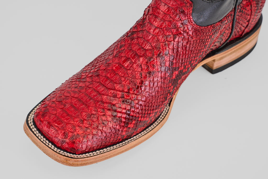 A close-up of the Tanner - Ruby - Square Toe cowboy boot, showcasing its Python Rojo snakeskin, square toe design, and detailed stitching on a light background.
