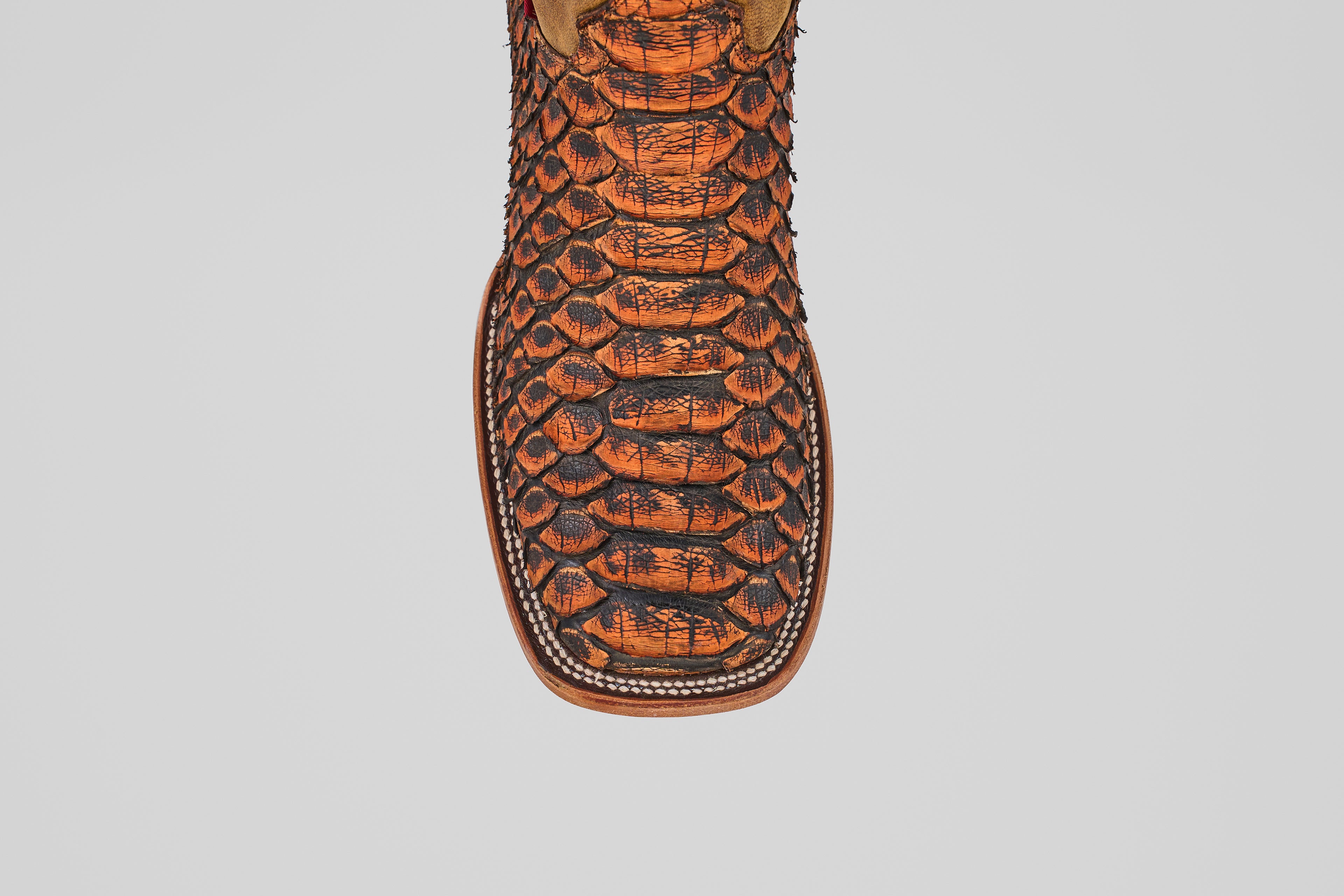 A close-up of the Tanner Jumbo – Chestnut – Square Toe boot, featuring a premium orange and black python snakeskin texture on the toe, showcased against a plain white background.