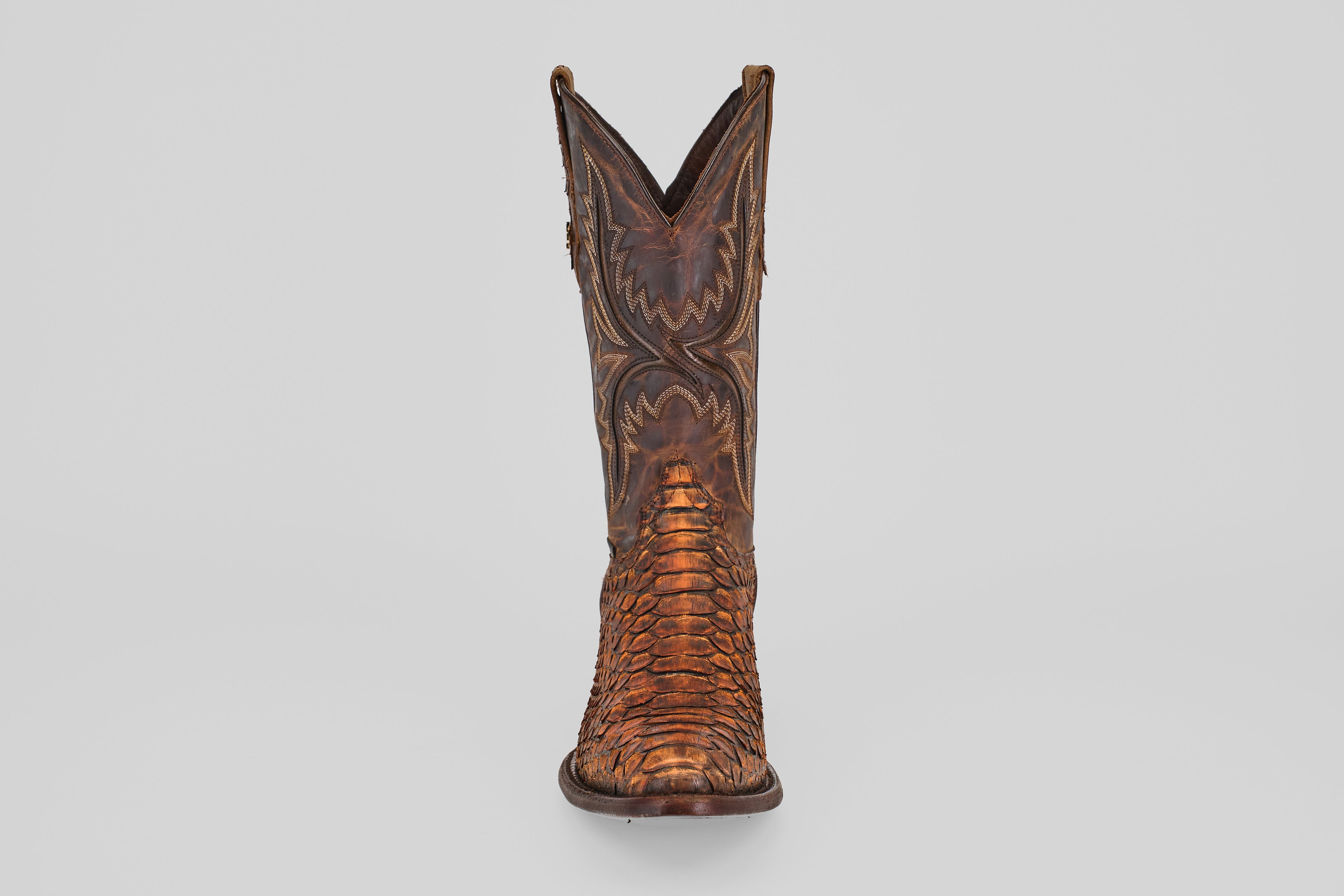 The Tanner – Chestnut – Round Toe cowboy boot features intricate stitching and a python-inspired textured pattern, shown facing forward on a white background—ideal for adding western flair to your style.
