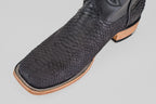 A close-up of the Tanner - Matte Black - Square Toe cowboy boot with python negro snakeskin and a light brown wooden sole, labeled PN30, set against a plain light background.