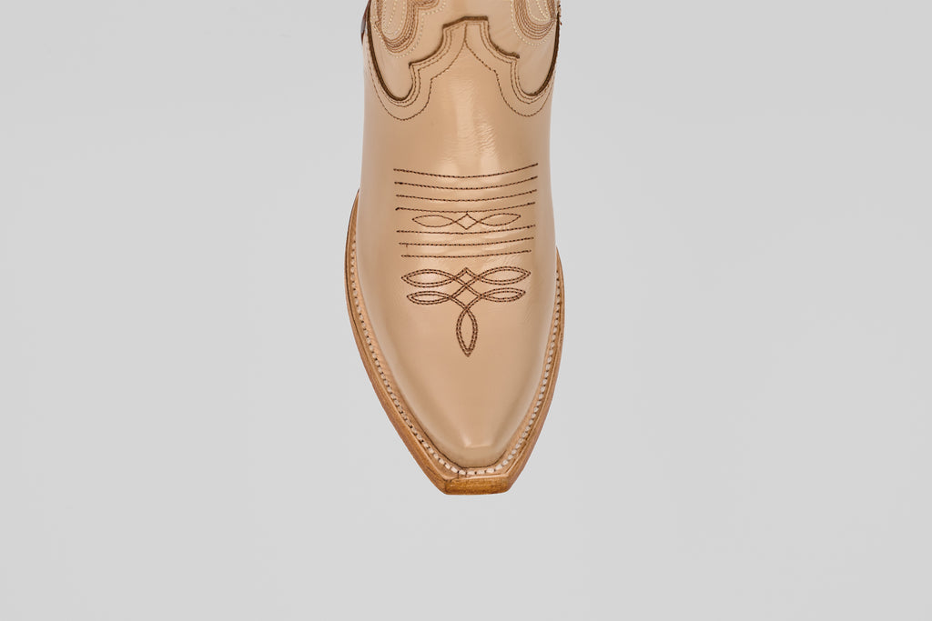 A close-up, top-down view of the pointed snip toe of the Allison Cream Tall Shaft cowboy boot, featuring tan leather and decorative stitching on the upper. A plain white background highlights these stylish women’s boots.