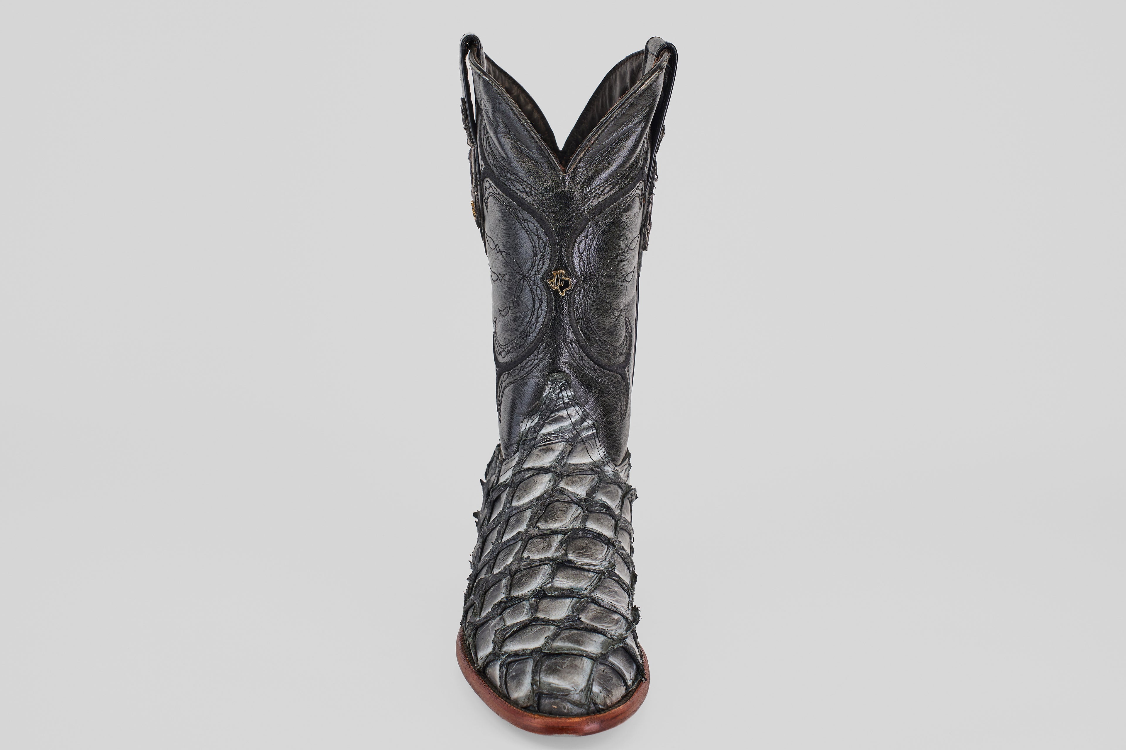The Conor - Newspaper - Roper Toe boot features black exotic leather with a textured, scaly pirarucu-inspired pattern and intricate shaft stitching, displayed upright on a plain white background.