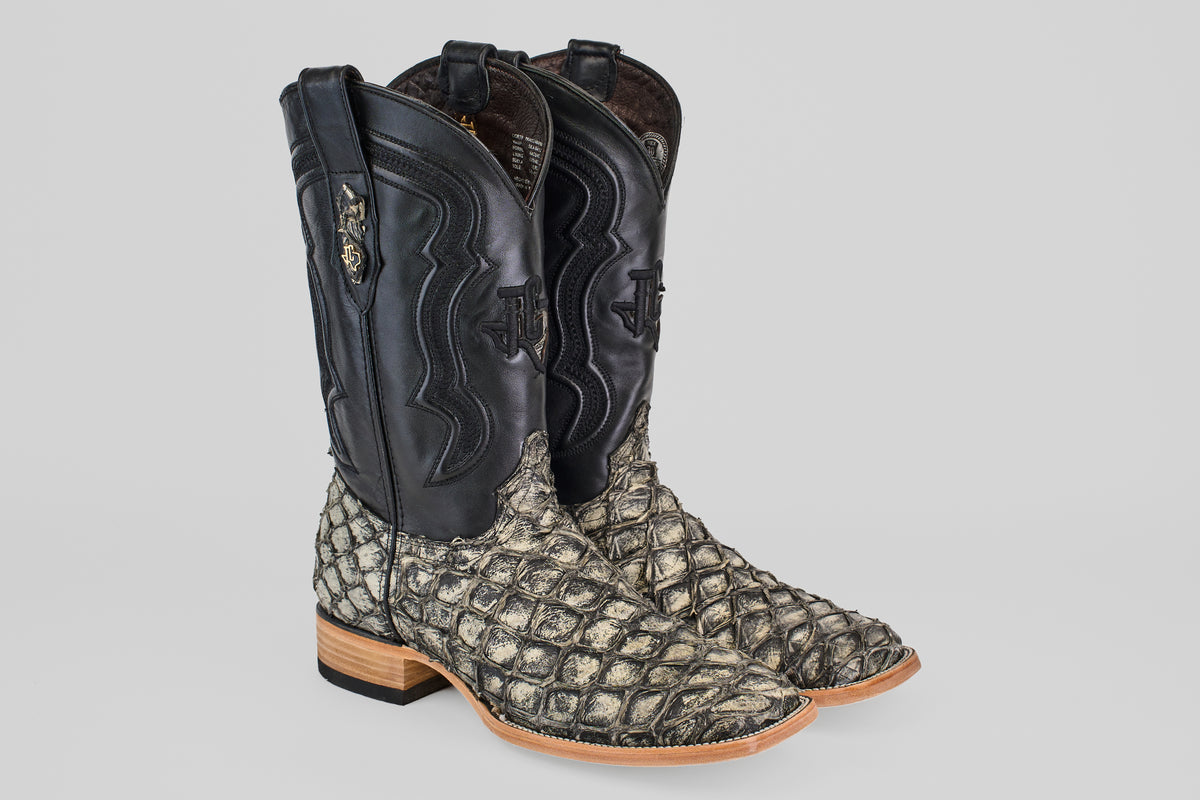 The Conor - Rustic Bone - Square Toe men's cowboy boots feature black leather uppers, rustic bone textured exotic fish leather lowers, wooden soles, and decorative stitching on the shafts.