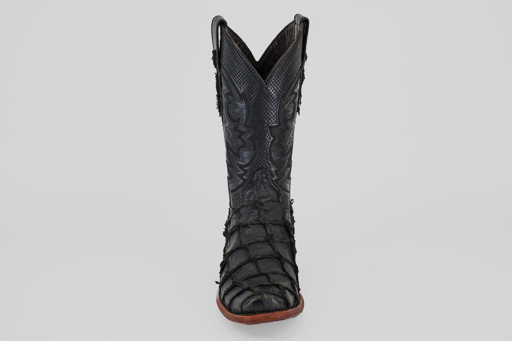 The Conor - Matte Black - Narrow Square Toe cowboy boot features textured, patterned fish leather and a brown sole, displayed upright and facing forward on a plain light gray background.