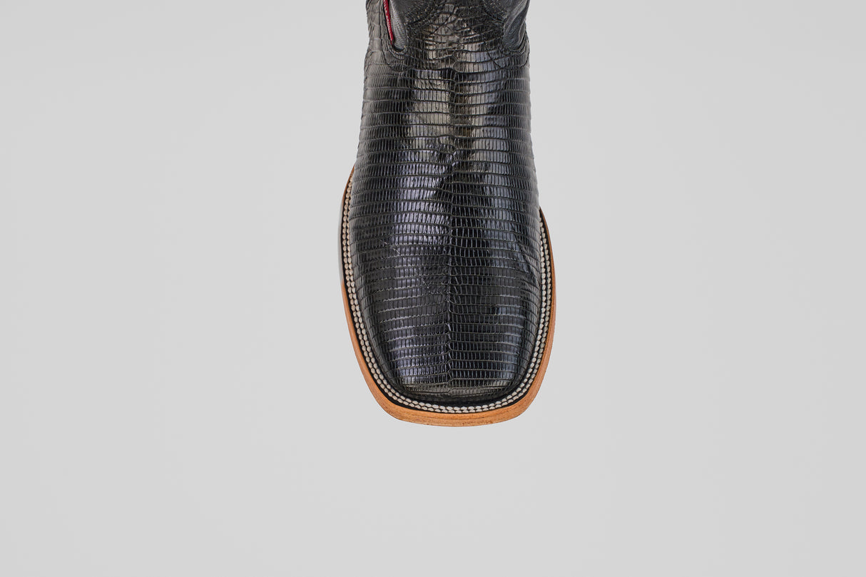 A close-up, top view of the Blaze – Black – Square Toe boots highlights their textured genuine black lizard leather with brown trim, set against a plain light gray background.