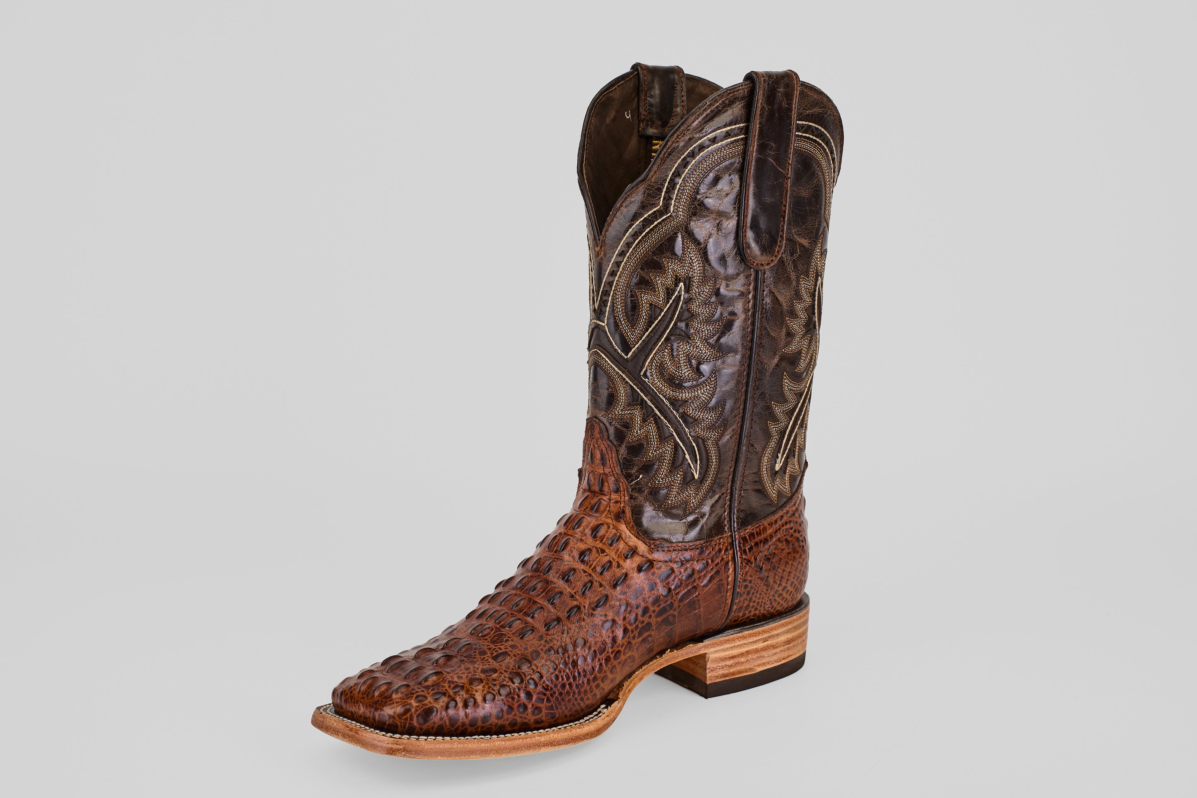 A single Hornback Brown - Embossed Leather - Square Toe (E427) boot, featuring a textured ostrich-leather lower and a darker, intricately stitched upper, is displayed against a plain light gray background.