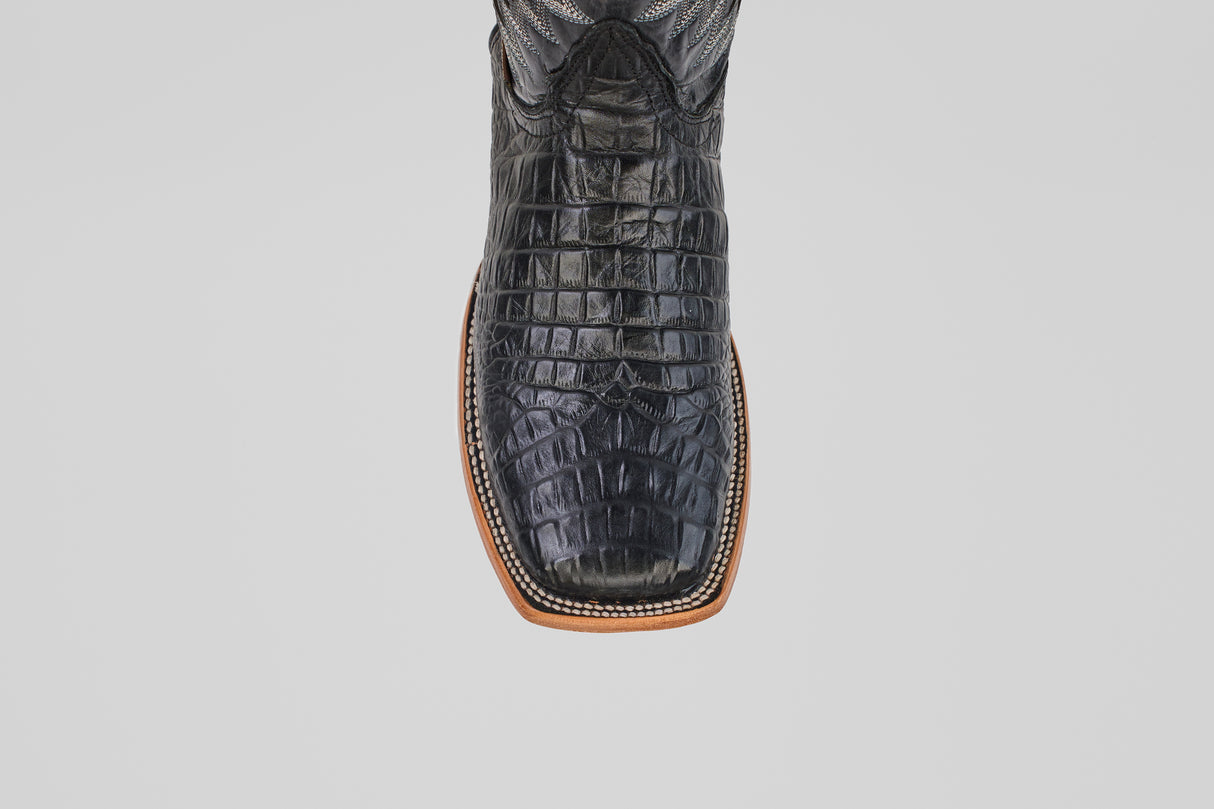 A top-down close-up of the Caiman Belly Black - Embossed Leather - Square Toe (E423) boots highlights the square toe, light brown sole, and bold black crocodile-embossed leather on a plain white background.
