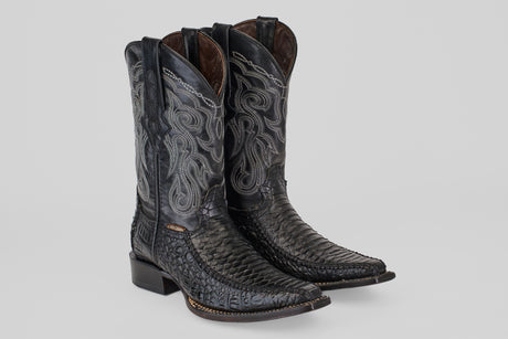 A pair of Python Black - Embossed Leather - Versy Toe (E202) cowboy boots with intricate silver stitching, pointed toes, and stacked heels is displayed on a plain light gray background.