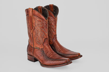 A pair of Lizard Cogñac - Embossed Leather - Versy Toe (E201) cowboy boots, showcasing intricate stitching and patterned texture with pointed toes and block heels, displayed against a plain light gray background.