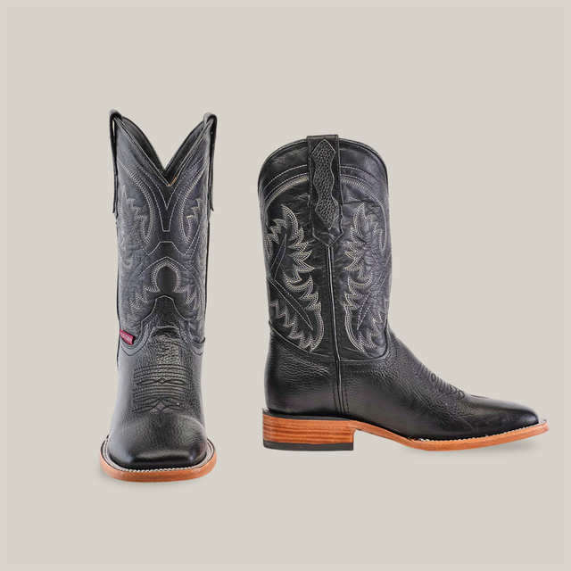 Two handcrafted Barcelona Black - Square Toe cowboy boots display detailed stitching on premium cowhide leather. One boot faces front, the other is side-viewed, showcasing a brown heel and sole on a crisp white background.