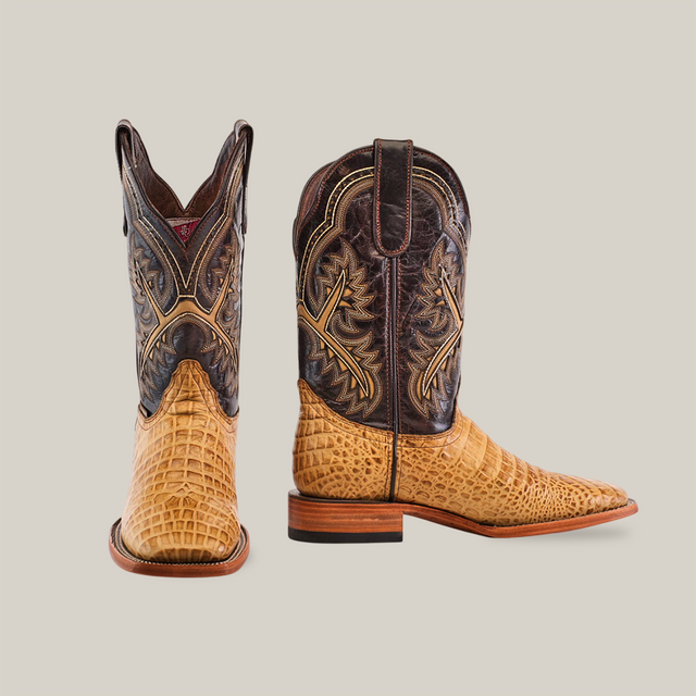 The Caiman Belly Print Orix - Square Toe boots feature intricate dark brown stitching on a textured light tan caiman belly print. One boot showcases its front, the other its side profile, both with wooden soles.