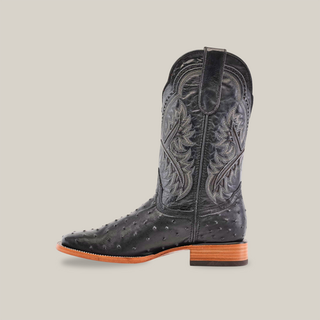 Introducing our handcrafted Karoo Ostrich Print Black - Square Toe boots, featuring intricate stitching on the upper shaft and a textured surface. These black cowboy boots have a medium brown heel and sole with slight angled detailing, all set against a plain white background.