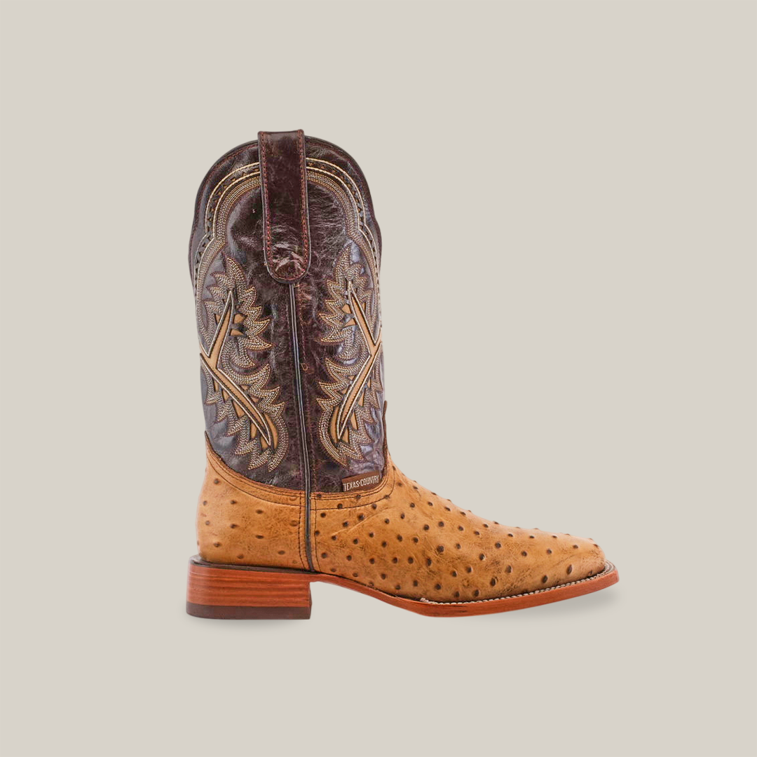 The Karoo Ostrich Print Orix - Square Toe boot features a premium cowhide design with a tan ostrich print foot, a dark brown shaft with ornate stitching, a wooden heel, and smooth leather sole, all set on a plain white background.