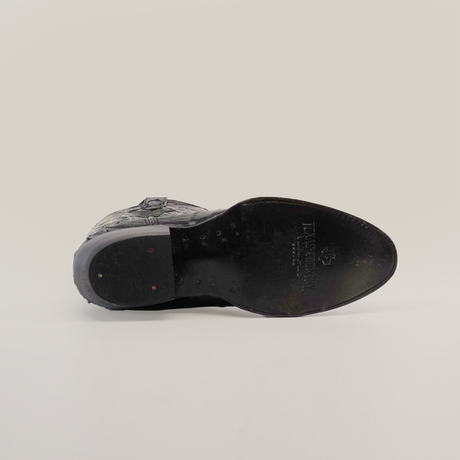 The image displays the sole of the Crocodile Tail Print Black - Round Toe shoe. It has a textured grip pattern with a logo and text imprint. The heel is secured with visible small nails, all set against a plain white background for clarity.