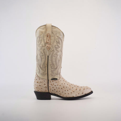 This handcrafted Karoo Ostrich Print Bone boot features a light tan leather upper with intricate stitched patterns and an ostrich print foot. It has a dark brown leather sole and heel, providing a striking contrast to the light finish.