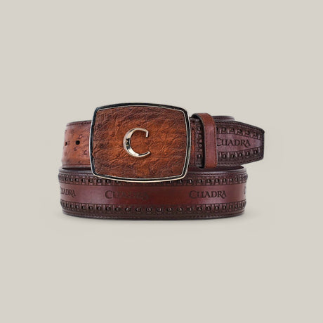 The Moroni Chestnut Ostrich Laser & Woven Belt - BC278 features a brown leather design with an embossed pattern, a large rectangular buckle with a gold letter C, and displays the brand name CUADRA, coiled to highlight its luxurious craftsmanship.