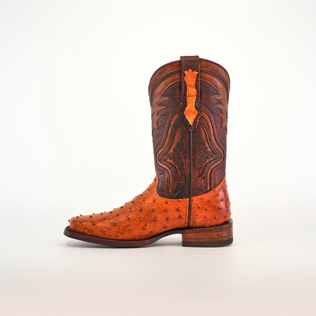 The Exotic Ostrich - Brandy boot features remarkable craftsmanship with a brown upper adorned with intricate stitching and an orange textured lower. Made likely from ostrich leather, it has a low heel and a pull tab for convenience.