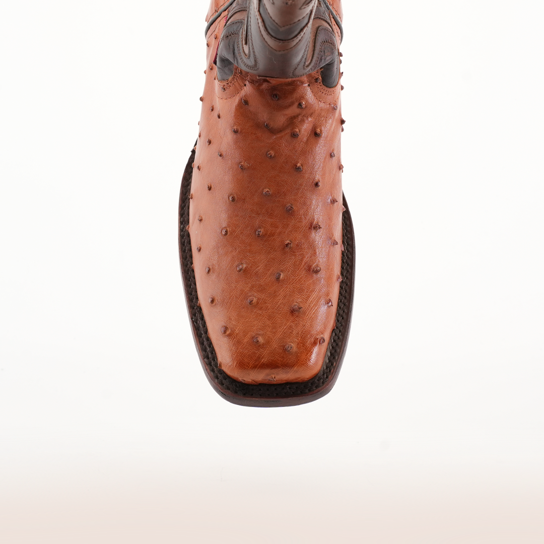 A detailed view of the Exotic Ostrich - Brandy - Rodeo Toe cowboy boot highlights its superb craftsmanship and unique bumpy ostrich leather texture. The brown boot features a rodeo toe and intricate stitching, presented against a plain white backdrop.