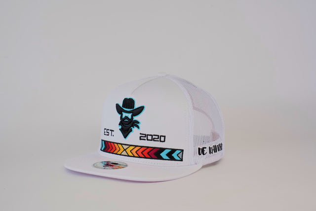 The De Rancho Cap Cowboy White is a white trucker hat featuring a stylized cowboy logo, EST. 2020, colorful tribal patterns, bold brim text, and intricate embroidery. Its mesh back enhances the Western heritage style, perfect for embracing ranch life.