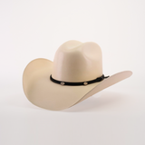 The 1000X Chihuahua Straw Hat is a durable beige cowboy hat with a wide brim, featuring a black band with silver buttons. Crafted from premium materials, it makes a bold fashion statement against the plain white background.