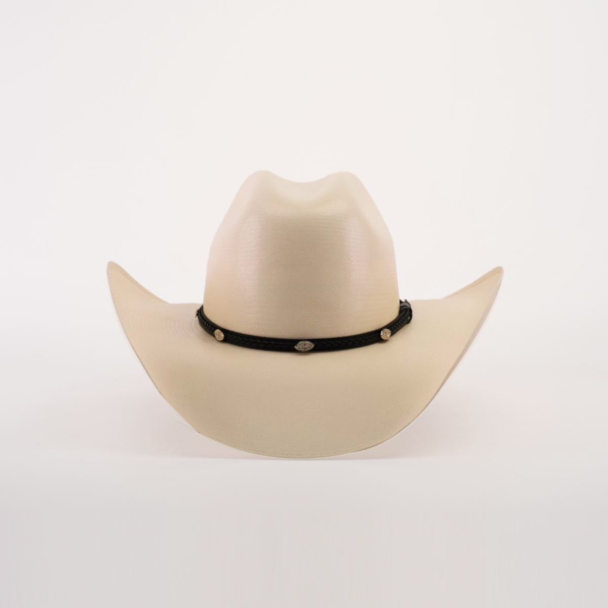 The 1000X Chihuahua Straw Hat, beige with a wide brim and accented by a black band featuring small oval conchos, stands out against a white background, offering a bold fashion statement for those seeking style and durability.