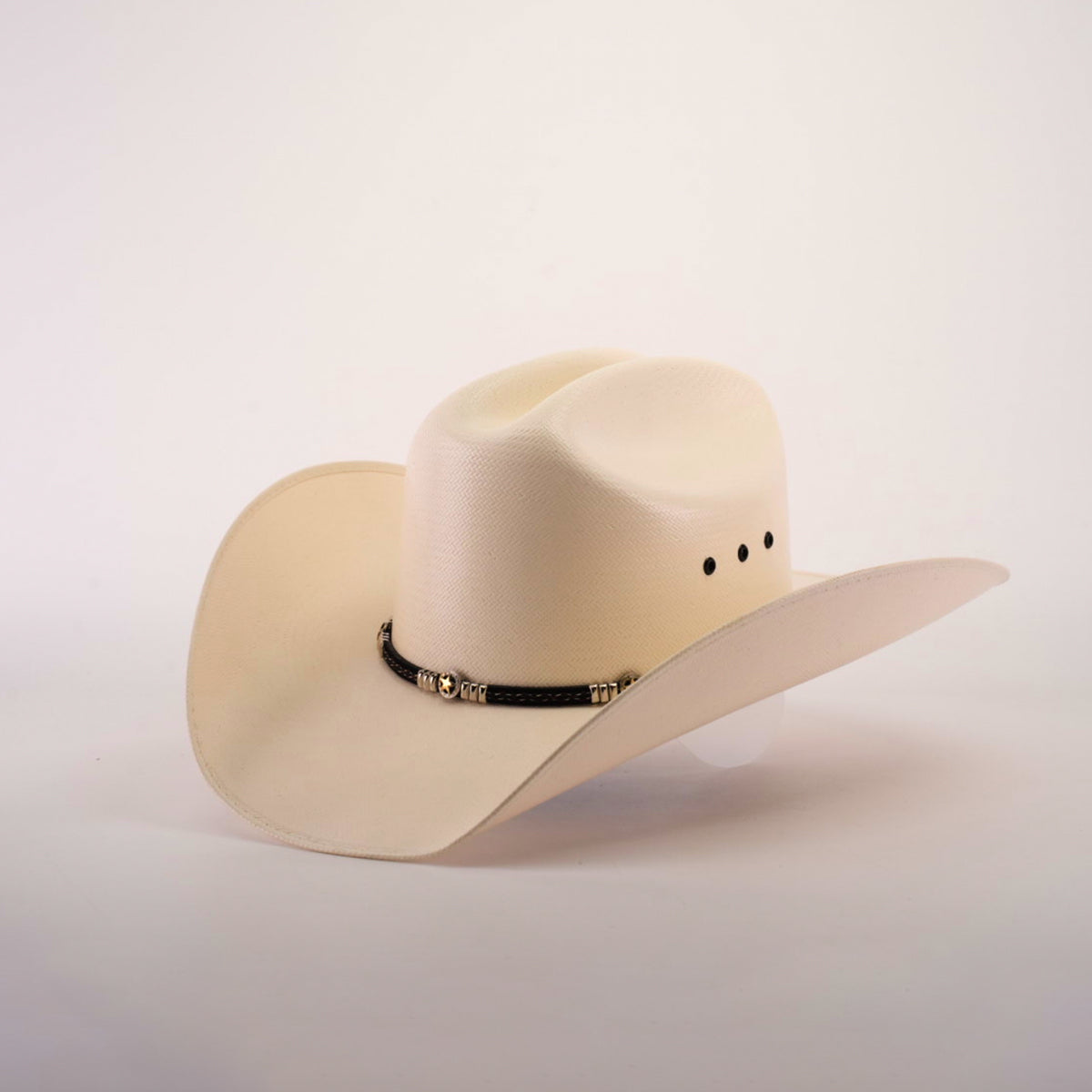 The 500X Country Straw Hat is a cream-colored cowboy hat with a classic design, showcasing a wide brim and adorned with a black band with metallic accents, made from premium materials, set against a plain white background.