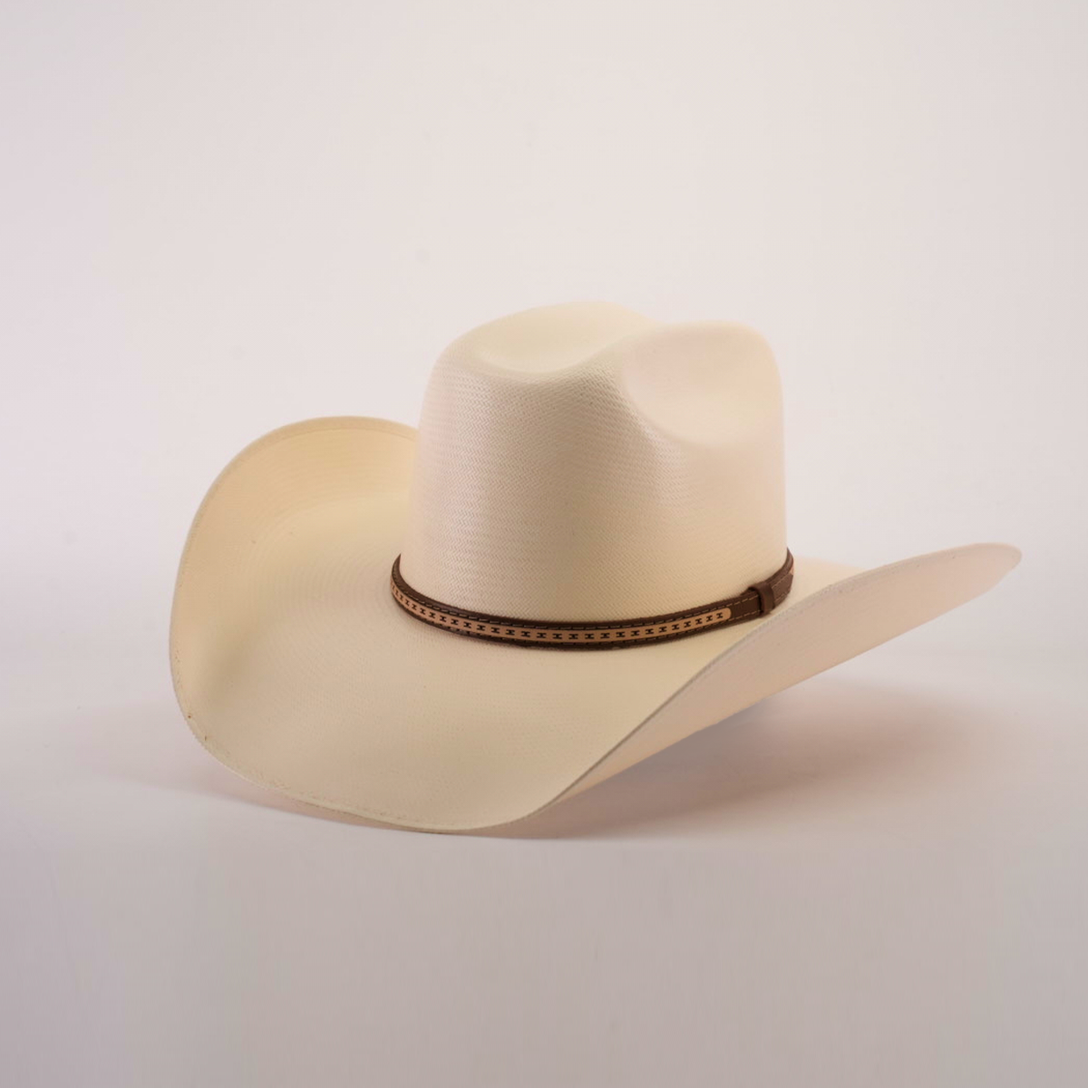 The 1000X Bull Straw Hat features a wide, curved brim and a brown decorative band, offering durability for outdoor adventures. Its light beige hue stands out against the plain white background.