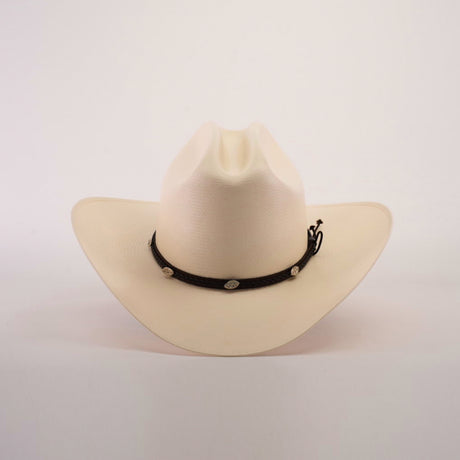 The 1000X Sinaloa Straw Hat features an elegant design with a wide brim, a black band adorned with silver conchos, and a plain white background.