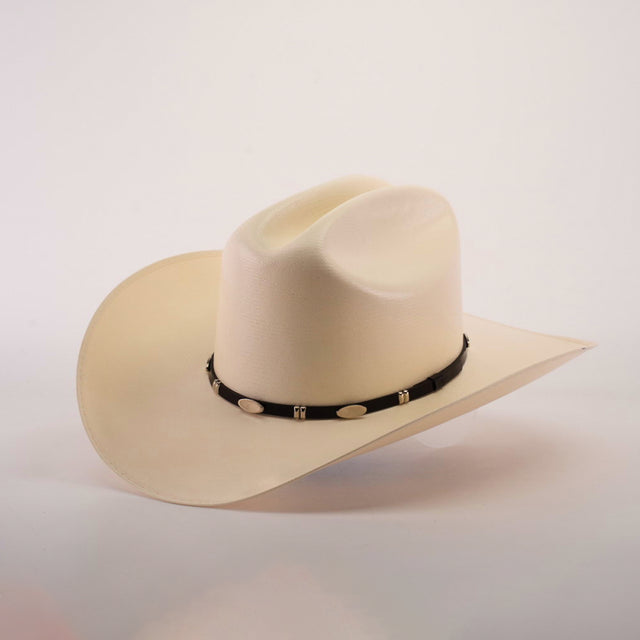 The 5000x Sinaloa Straw Hat, featuring a wide brim and black band adorned with silver oval decorations, exudes elegance and fine craftsmanship as it sits against a plain light background.