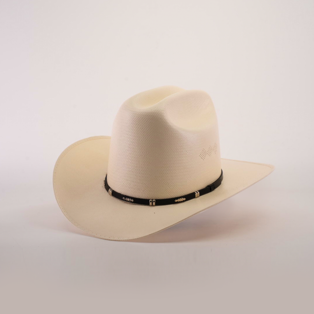 The 500X Dos Carnales Straw Hat, renowned for its quality and durability, boasts a wide brim with a black band at the base. Positioned perfectly on a plain, soft backdrop, this light cream-colored cowboy hat exemplifies style and function.