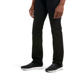 A person models M7 Slim Legacy Straight Jeans in black paired with black sneakers featuring white soles, set against a white background. The image highlights the lower half of the body, showcasing both legs and feet.