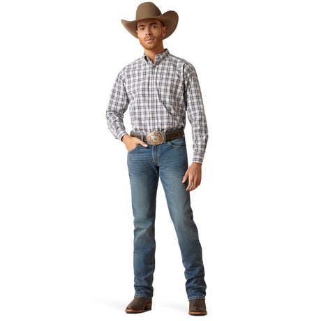 A modern cowboy exudes confidence in his M7 Slim Ezra Straight Jeans - Brighton (10045388), paired with a plaid shirt, boots, and classic cowboy hat. His large belt buckle gleams subtly against the plain white background as he casually rests a hand in his pocket.