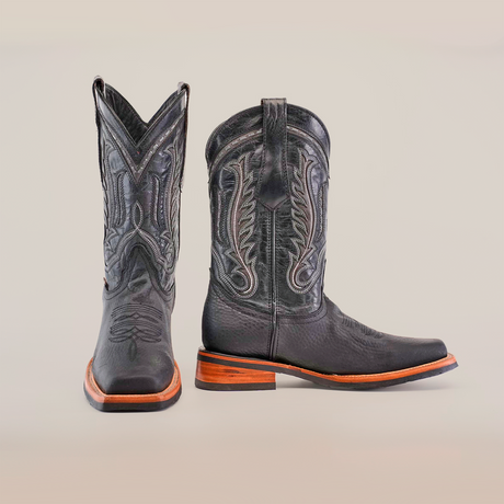 The Cheyenne Black boots feature premium cowhide leather and intricate stitching, with a Rodeo toe and wooden heels. Displayed stylishly against a white background, they offer practicality with a slip-resistant sole.