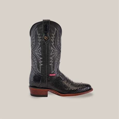 The Exotic Python - Black - Round Toe boot showcases handcrafted details with ornate stitching and a luxe Python leather texture. It includes a small red label near the sole, brown heel, and is set against a plain, neutral background.