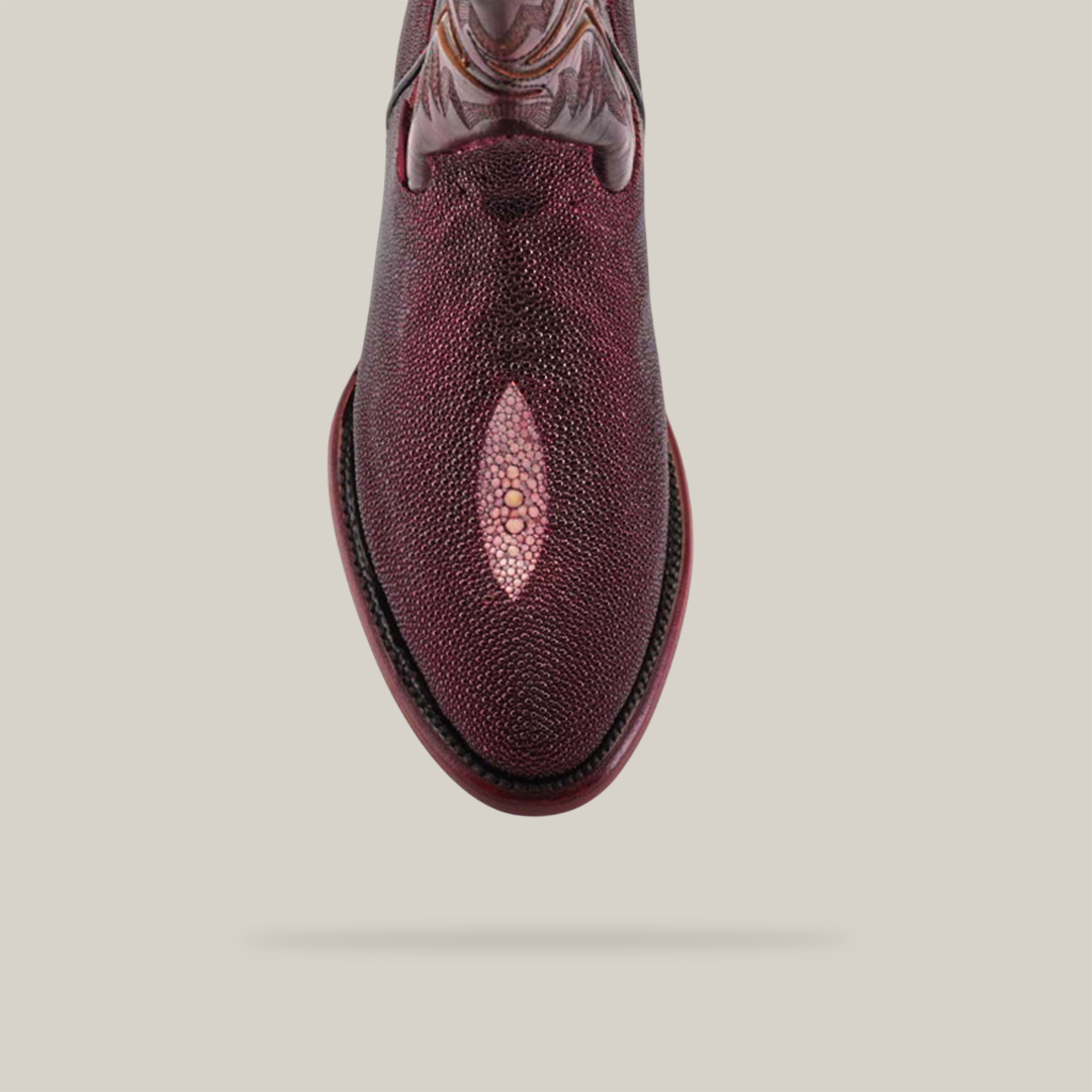 Top view of an Exotic Stingray - Wine - Round Toe boot, showcasing its textured maroon leather and detailed ankle patterns. The luxury boot includes a central oval accent on a plain light gray background with a subtle shadow.